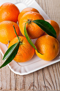 盘子里有叶子的橘子桌子宏观水果果汁团体橙子饮食片段木头季节图片