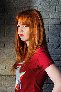 在墙前发怒的红头发 毛发发色发光的姑娘图片