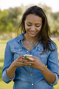 美丽的女性发短信幸福牛仔裤呼唤微笑讲话短信公园技术电话女孩图片