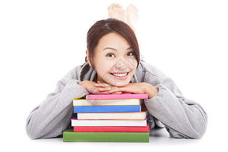 躺在堆叠的书本上的年青亚洲学生中学大学笔记本女性青少年学校文凭阅读图书馆幸福图片