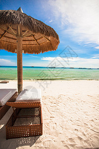 热带沙滩上的草伞太阳阳光闲暇季节晴天阳伞支撑蓝色假期旅游图片