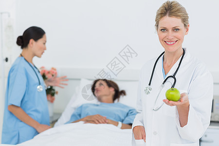 将苹果与住院病人一起保存在医院的微笑医生绿色保健卫生女士水果外科女性病房医疗从业者图片