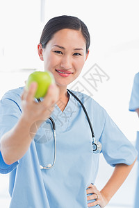 微笑的女外科医生在医院里拿着苹果图片