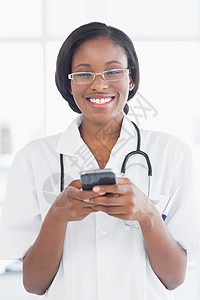 医生手机手持移动电话的微笑女医生医疗快乐手机医务室女性电话沟通制服女士短信背景