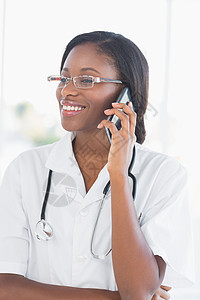 使用移动电话对女医生进行微笑制服呼唤医疗电话快乐女性女士沟通拨号医院图片