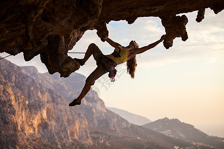 日落时的攀岩者太阳洞穴高度登山者岩石女性运动绳索女孩悬崖图片