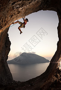 日落时女性攀岩者悬崖绳索高度女士太阳登山者活动风景天空运动图片