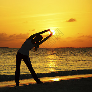 妇女伸展在日落海滩上背景图片