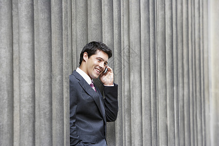 商业人员在手机界柱之间站在外面的建筑外使用连接短发位置微笑黑发城市天台成年外观图片