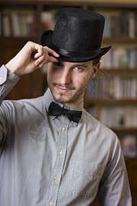 穿着顶顶帽子和领结的迷人年轻男子男人男性白色贵族黑色夹克套装绅士成人魔术师图片