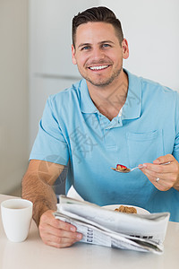有报纸在餐桌边吃早餐的男人图片