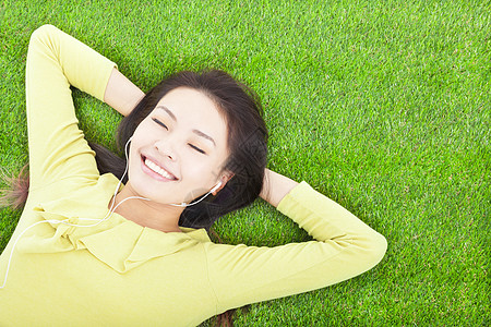 微笑的女士抱着头 躺在草地上图片