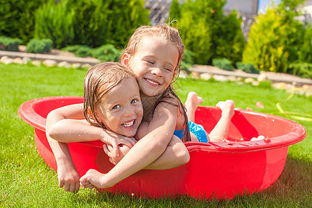 两个可爱的小快乐女孩 在夏日户外小游泳池玩得开心童年娱乐后院孩子微笑幸福晴天婴儿闲暇草地图片