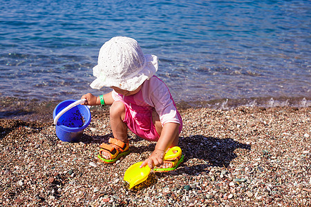 海上的婴儿游戏孩子卵石闲暇泳装海岸线太阳支撑玩具家庭女孩图片