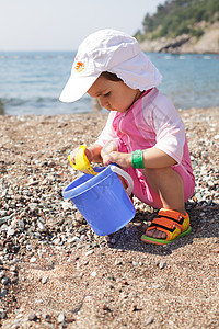海上的婴儿游戏海岸线游泳衣女孩家庭假期泳装海滩太阳孩子卵石图片