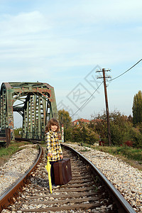 在铁路上拿着雨伞和手提箱的小女孩图片
