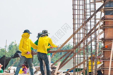 建筑工地的工人安装团队头盔平台勃起黄色职场地板建造男人背景图片