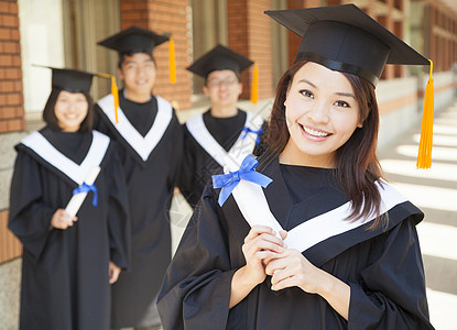 带着微笑的大学毕业生与同学持有毕业文凭图片