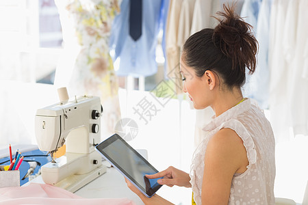 女时装设计师使用数字平板滚动药片造型师专注女性电脑工作屏幕裁缝女士图片