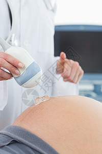 孕妇和医生医生对孕妇腹部使用超声波检查背景