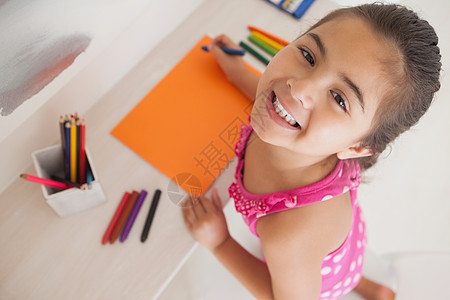 年轻女孩在橙色纸上画画混血桌子橙子艺术品童年爱好铅笔闲暇彩色绘画图片