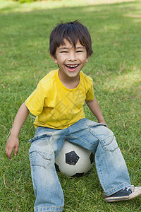 坐在公园足球场的可爱小男孩图片