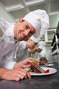 一排厨师在照相机上用一个微笑的笑容来加点甜点蛋糕烹饪职员巧克力厨房职业同事伙伴女性酒店图片