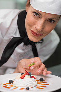 微笑的厨师在蛋白盘上放薄荷叶酒店美食大楼酥皮女性领带薄荷叶制服商业甜点图片