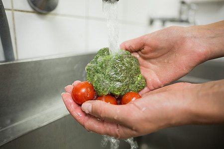 大厨在水龙头下清洗花椰菜和西红柿酒店职业绿色制服龙头工作卫生餐厅漂洗双手图片