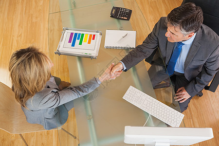 两个在办公桌上握手的商界人士女士管理人员生意人职员条形伙伴商务协议电脑记事本图片