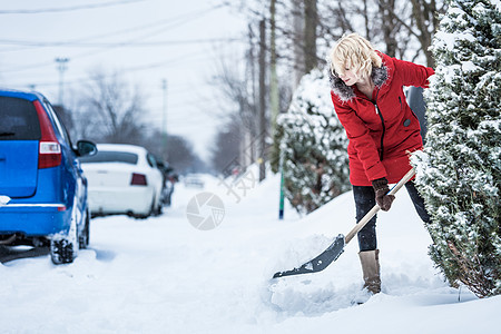 妇女冲洗她的停车场降雪雪花乐趣街道城市暴风雪女士季节气候薄片图片
