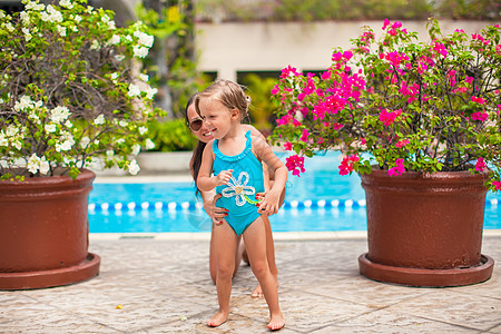 在豪华度假胜地露天泳池附近 带着年轻母亲的快乐小女孩图片