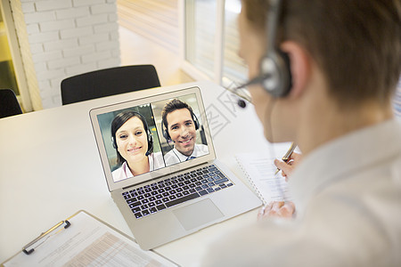 办公室与Skype头盔举行视像会议业务员工作桌子技术职场商业男人男性阅读学习商务图片