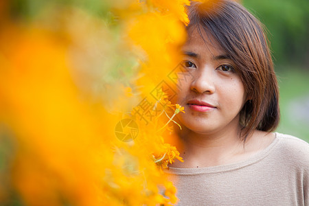 站在黄色花朵旁的亚洲肖像女性花园头发阳光叶子快乐晴天闲暇女孩公园季节图片