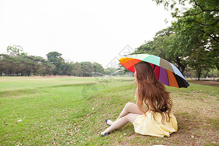 有雨伞的女人 坐在草坪上自由女性天空公园成人季节生活女孩草地花园图片