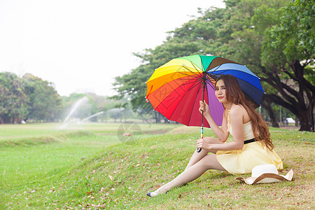 有雨伞的女人 坐在草坪上女性天气生活女士草地公园场地天空女孩季节图片