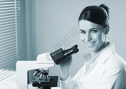 从事显微镜工作的女研究员保健微生物学制服实验大学生化学家微笑工作服验室职业图片