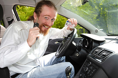 坐在车里笑着 展示新车钥匙和驱动器的驾驶员图片