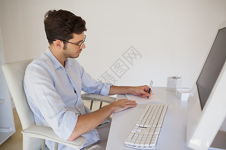 在办公桌旁做笔记的 临时商务人士商业职业休闲办公室男性笔记本衬衫屏幕记事本人士图片