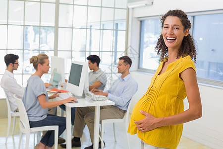 身孕怀孕的女商务人士对着镜头微笑伙伴孕妇装职业职员合作休闲女士合伙办公室男性图片