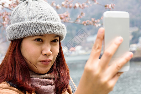 年轻快乐的亚洲女人正在看她的手机拍摄友谊女性电话冒充阳光喜悦女士幸福自拍图片