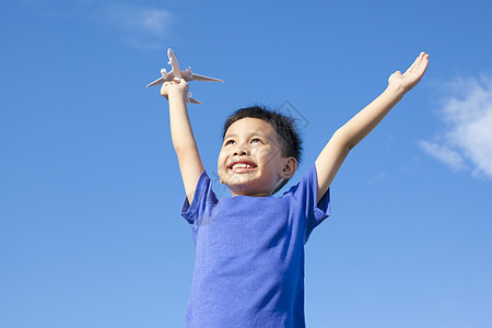 带着蓝色天空背景玩具的快乐小男孩儿图片