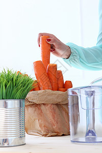 美丽的女孩做胡萝卜汁果汁花园维生素健康桌子女性混合器衣服萝卜机器图片