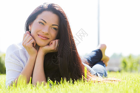 草地上美丽的女人发型太阳微笑女士黑发眼睛女性冒充说谎皮肤图片