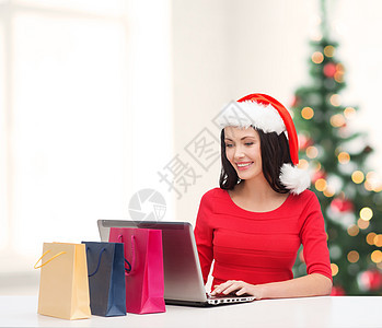 妇女用购物袋和膝上型电脑命令技术快乐礼物微笑销售互联网展示女孩购物图片