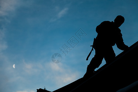在Silhouette的承包商在屋顶上工作职业工人男性建设者劳动装修建筑指甲月亮天空图片