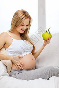 怀着新鲜绿苹果的幸福孕妇水果微笑母性女士沙发生态食物孩子维生素生物图片