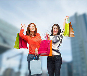 2个带着购物袋笑着的少女女孩青少年提倡者顾客购物狂财富中心消费者礼物建筑物商业图片