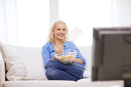 有爆米花的年轻女孩 在家看电影闲暇控制电影娱乐女士成人小吃沙发青少年食物图片