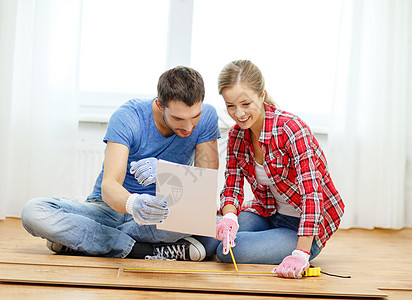 微笑的一对夫妇测量木地板统治者房间建筑女性铅笔阅读屋主夫妻男朋友男性图片